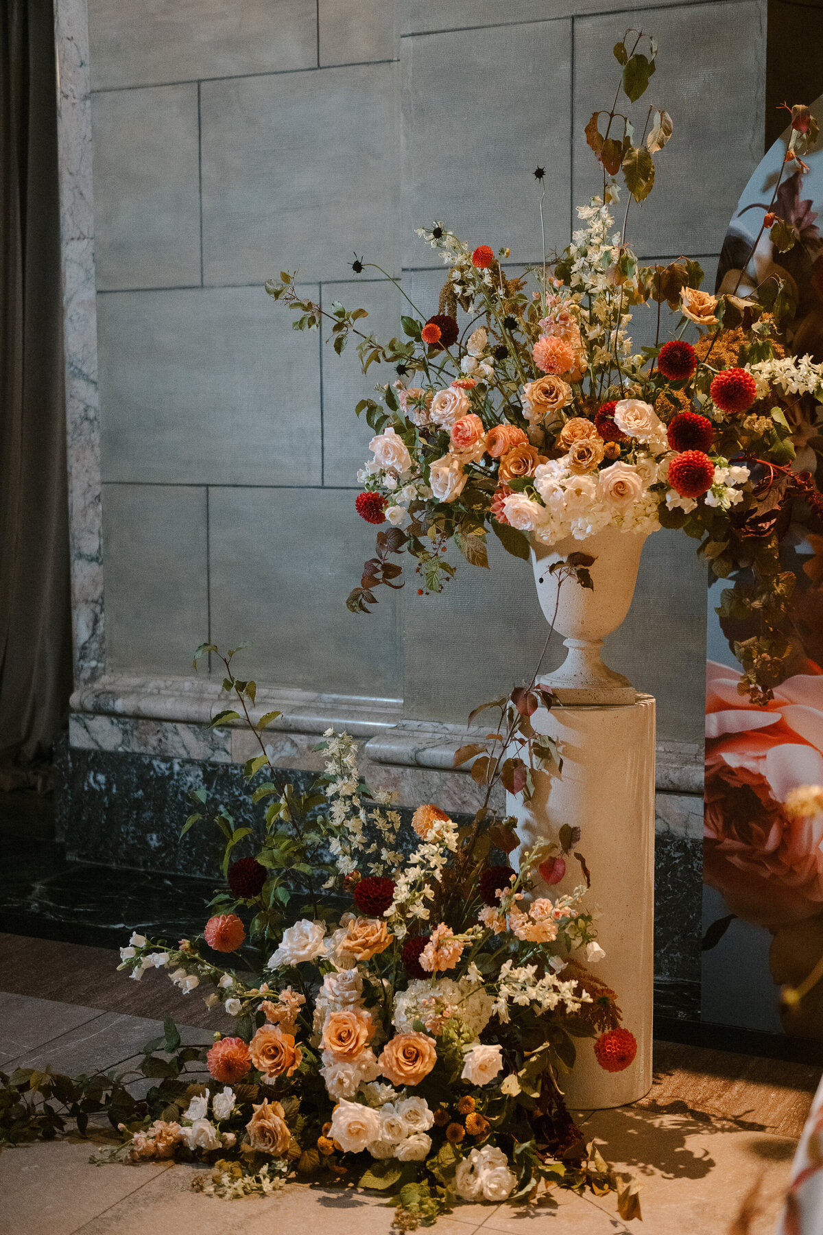 Beautiful garden arrangements of roses and dahlias in front of a marble wall at Theatre St James.
