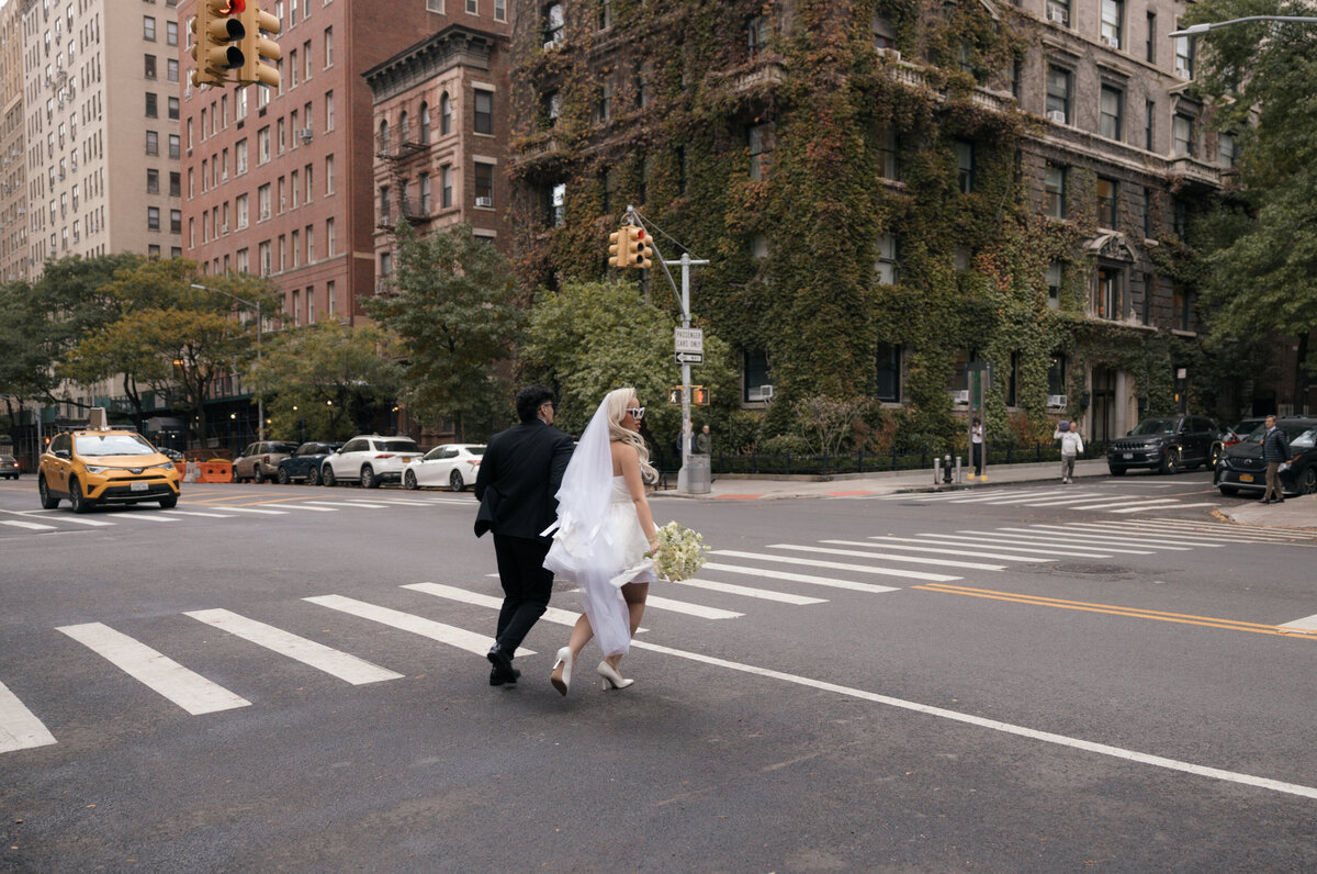 Elopement couple strolling through NYC streets with the skyline in the background.