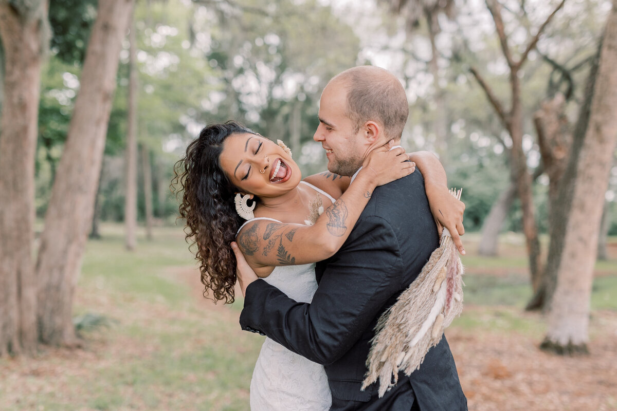 A Florida couple on their wedding day at a park in Crystal River, celebrating and laughing with each other during their Winter elopement on the Gulf Coast.