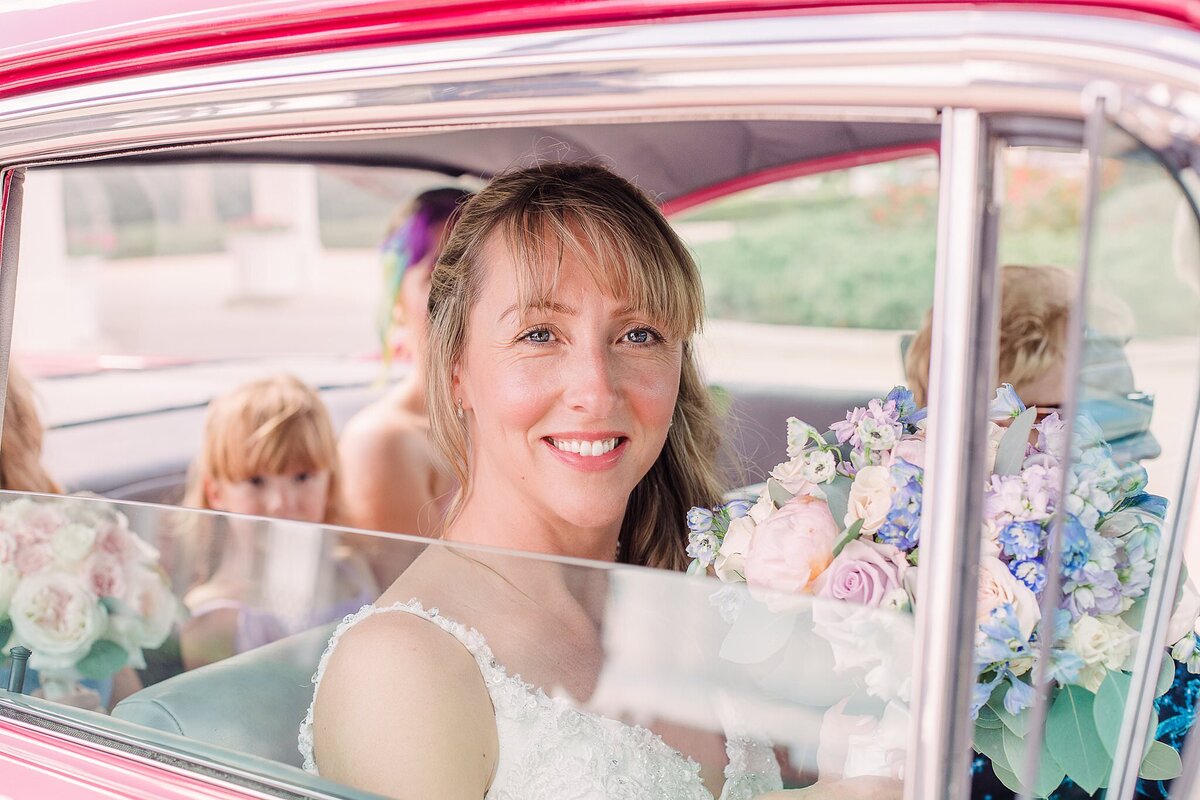 Bride smiles through window of vintage car at Disney Wedding Pavilion