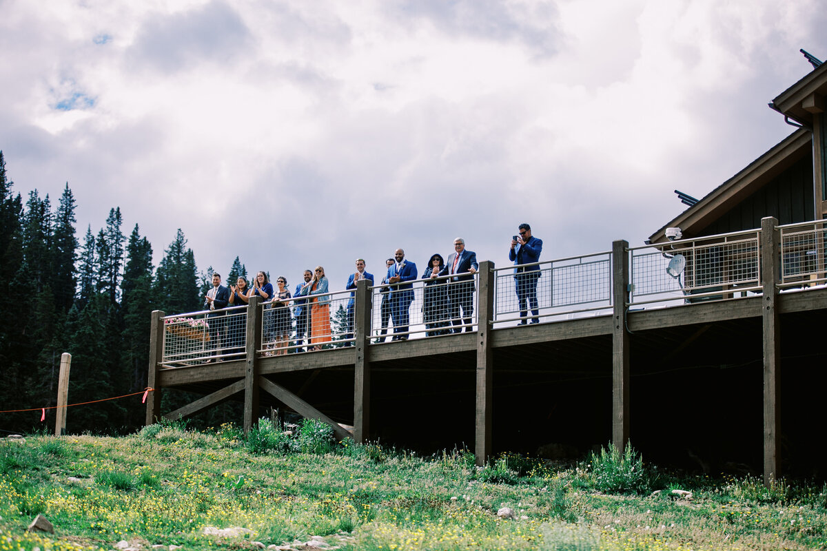 Family watches a wedding first look from the deck of the Black Mountain Losge wedding venue at Colorado's Arapahoe Basin