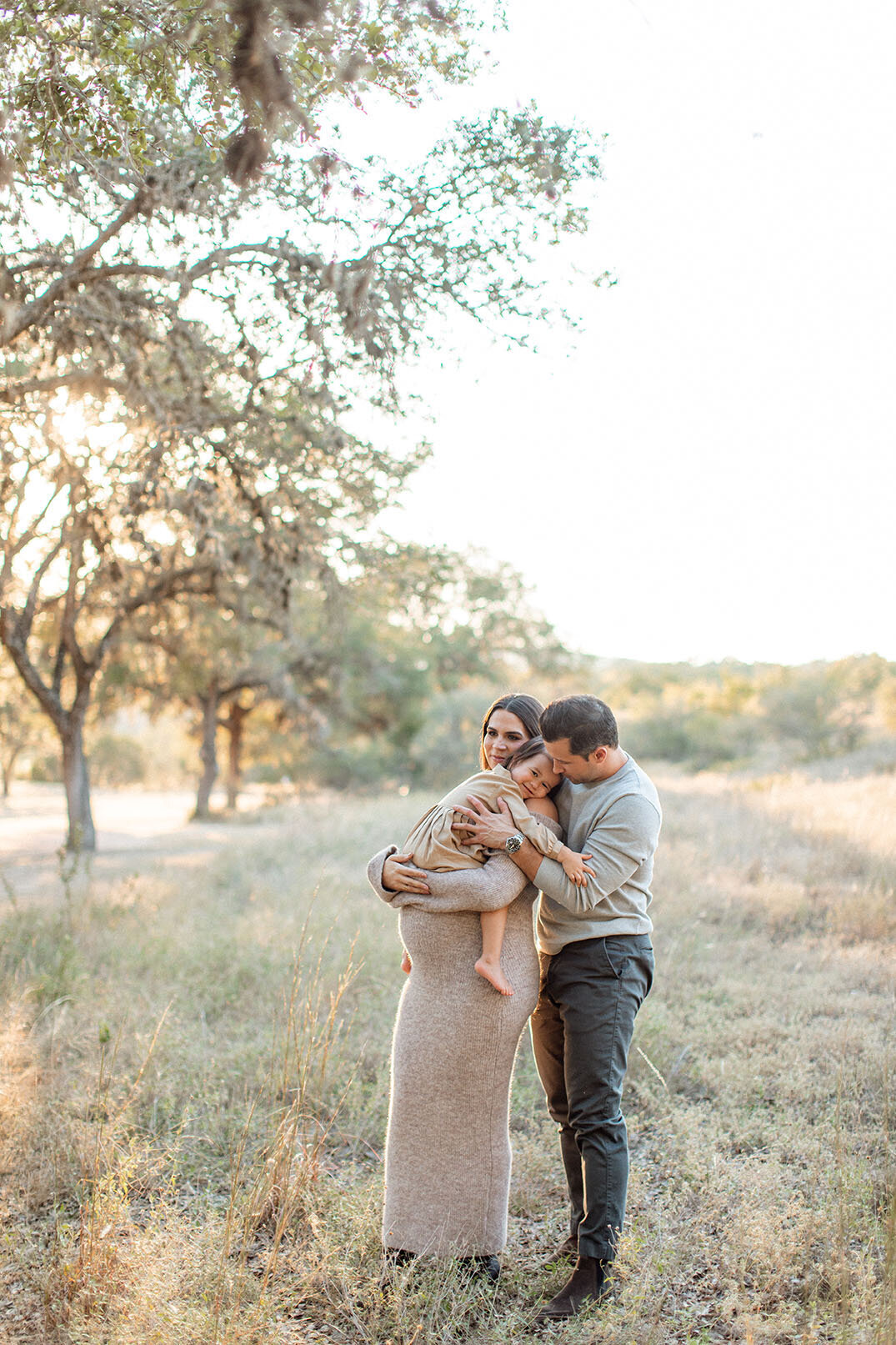 Maternity photo of a pregnant woman with her family in a field, photographed by San Antonio family photographer Sara James.