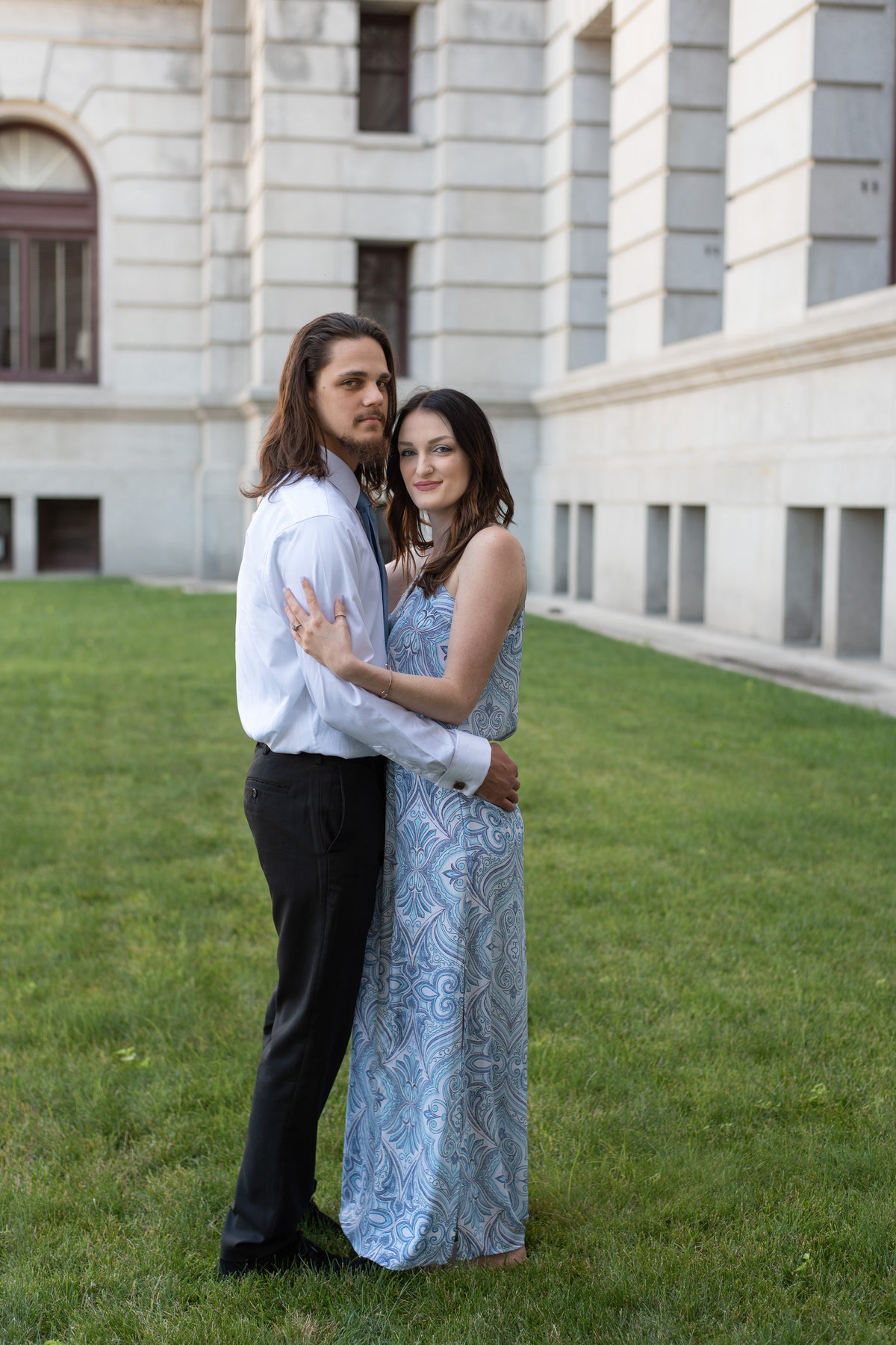 Engaged Couple in Dressy attire in front of white marble building