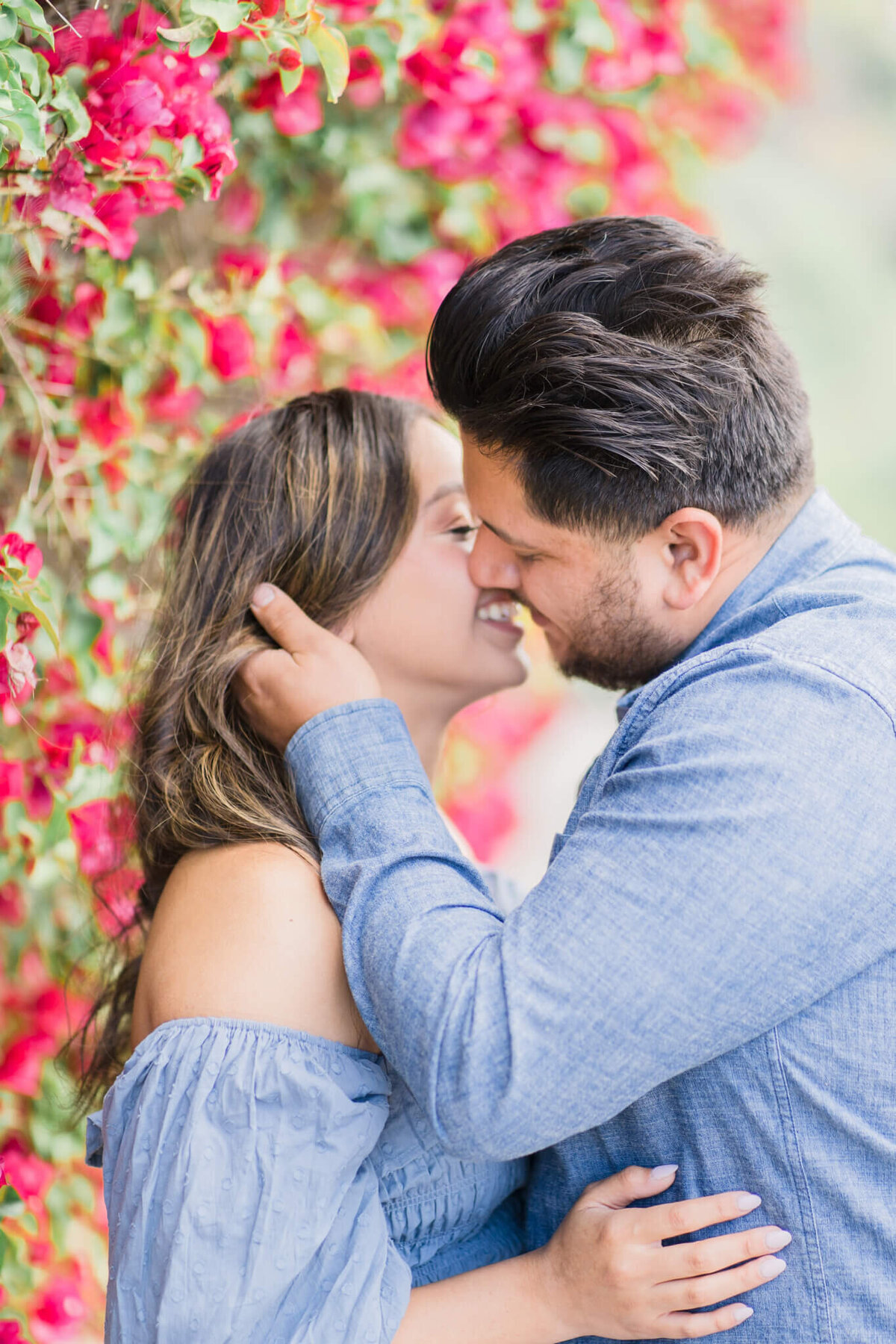 Couple kissing next to a wall of pink flowers