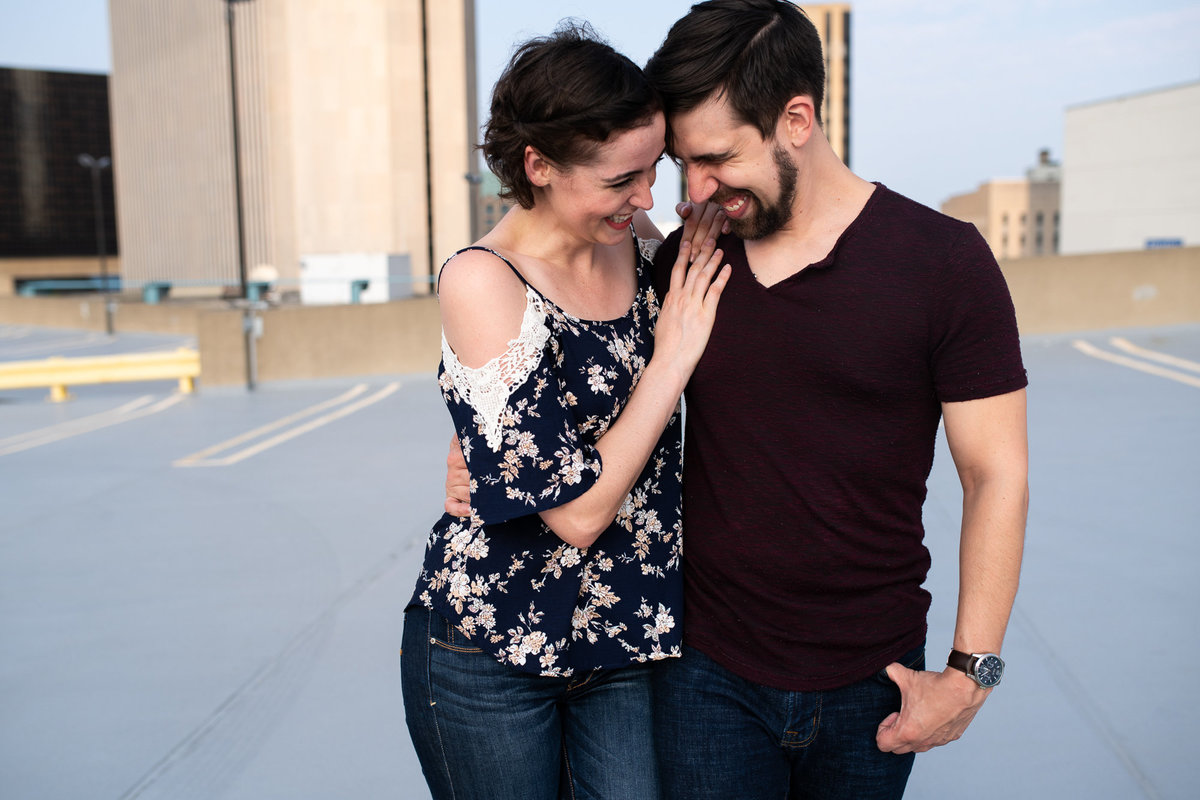Couple drunk walks on rooftop garage during engagement session