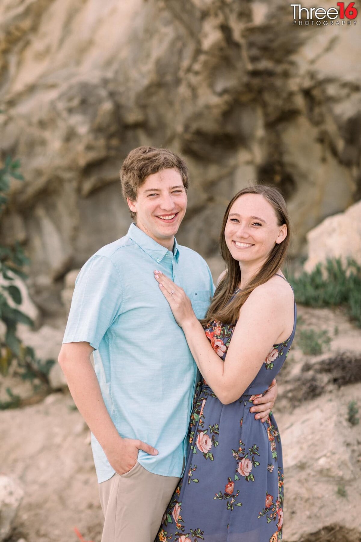 Engaged couple cozy up together during engagement photo session at Corona del Mar State Beach