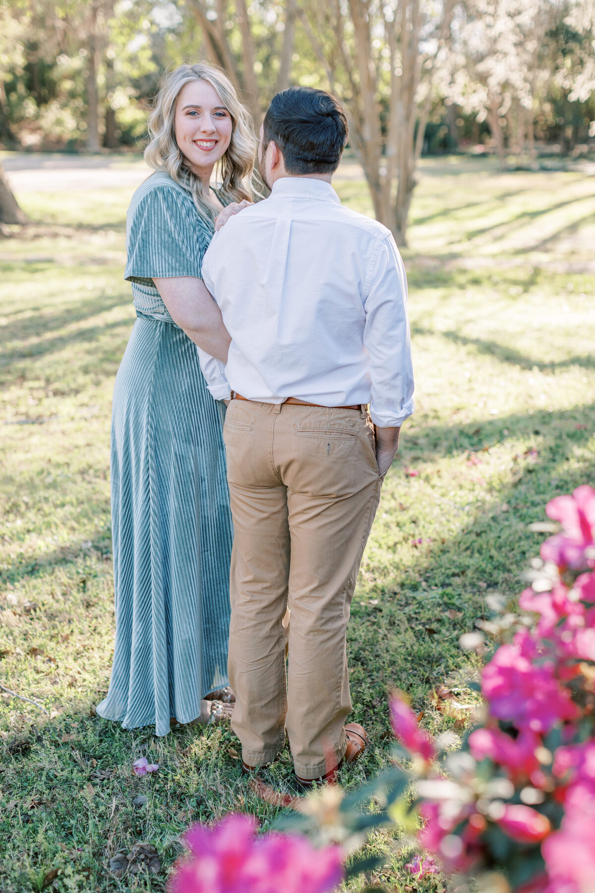 A couple stands next to each other for their spring engagement photos.