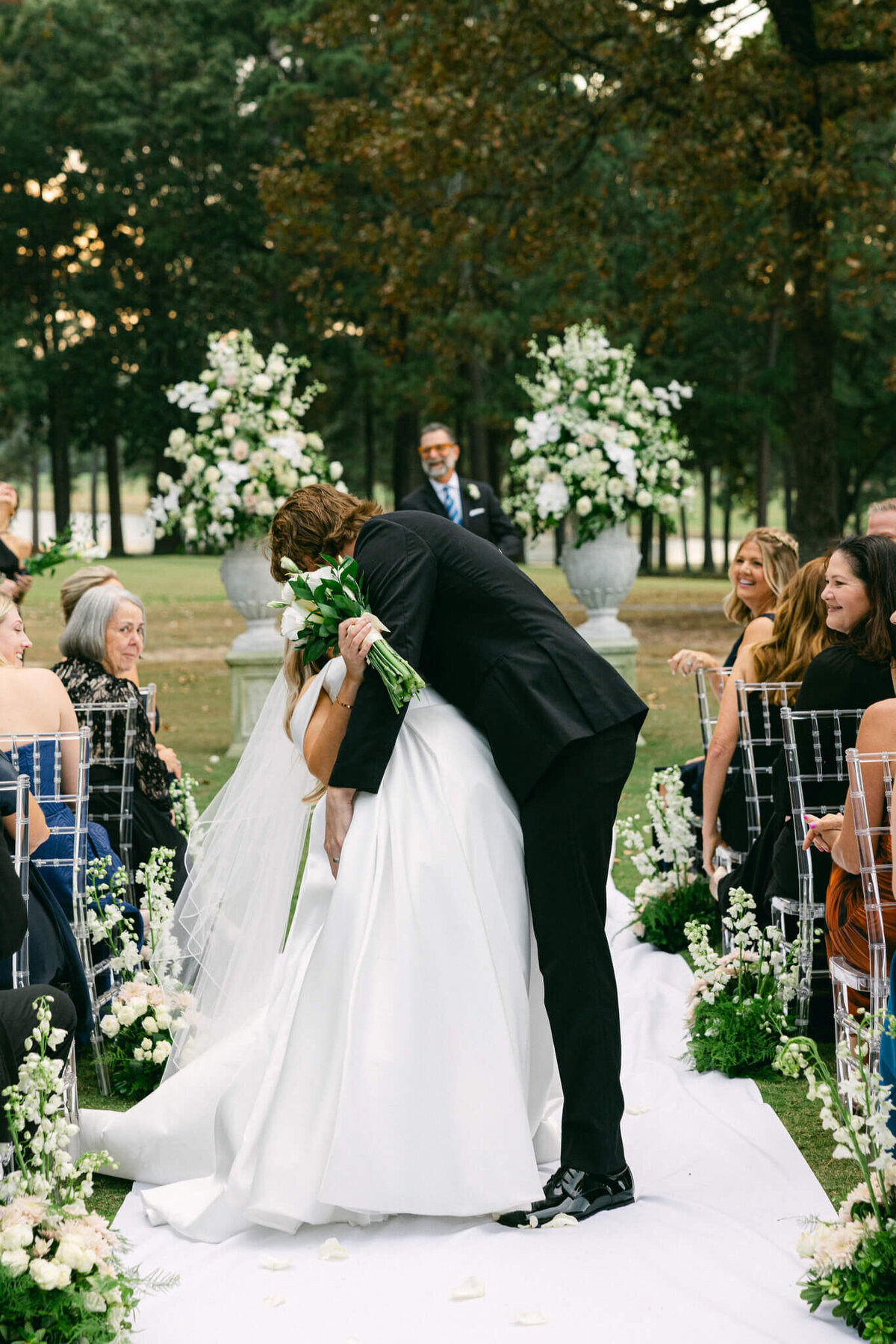 A wedding photo of the bride and groom kissing half way down the aisle after the ceremony