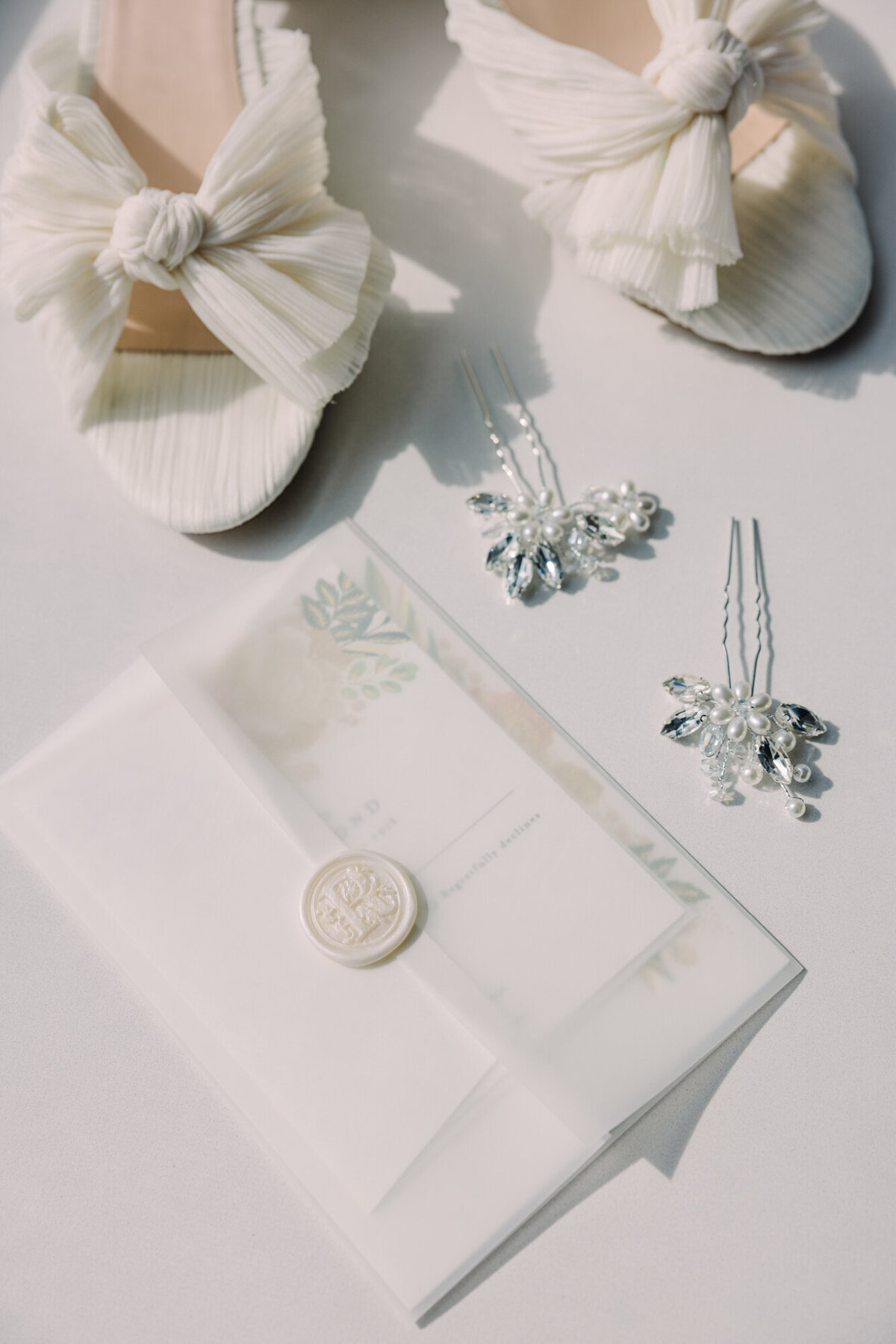 A delicate wedding detail shot featuring bridal shoes, an invitation suite, and elegant accessories.