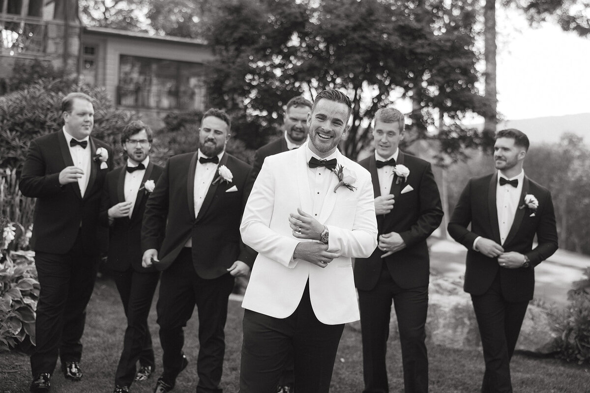 Groom laughing with groomsmen during portraits at Trillium Links & Golf Club in Cashiers, North Carolina.
