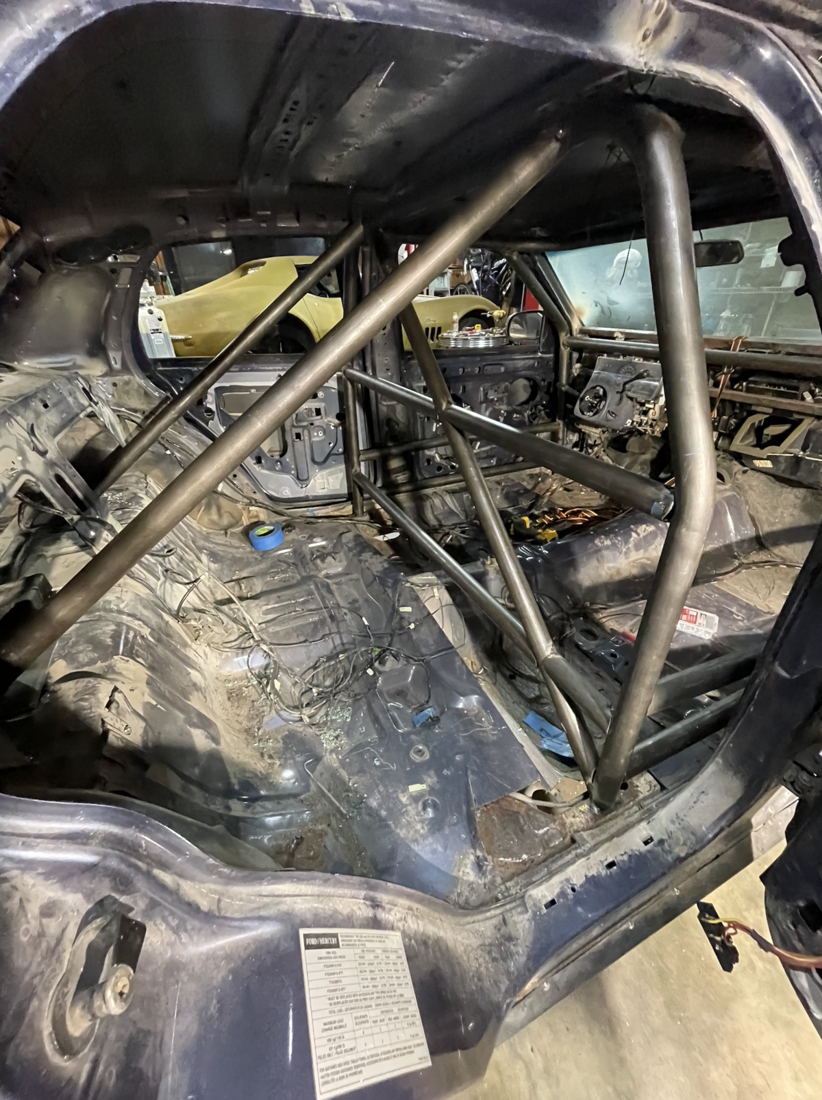 Fabricated and welded custom steel roll cage installed inside a car for enhanced safety and structural reinforcement.
