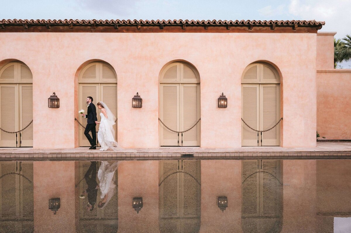 Bride and groom walking beside the reflecting pool at Royal Palms Resort in Phoenix, captured by luxury wedding photographers.
