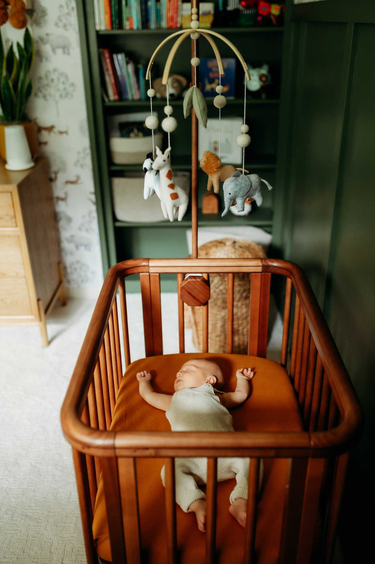 baby sleeps peacefully in a perfectly styled nursery, in warm tones and sweet clothes.