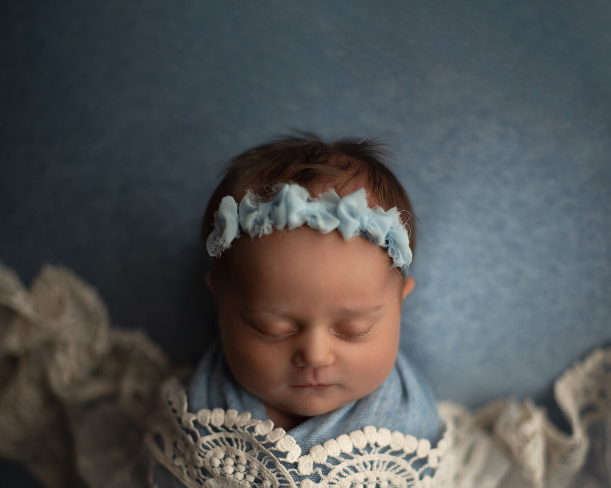 newborn snuggled in blue and lace