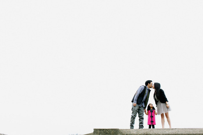 Wide angle shot of two parents kissing over young child between them