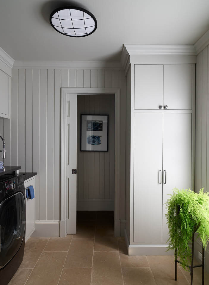 Explore the elegant laundry room in a historic Hingham home, featuring limestone flooring, custom grey cabinets, shiplap walls, and a new powder room.