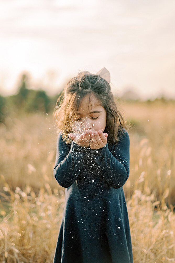 Toddler girl blowing glitter at her Christmas Photoshoot