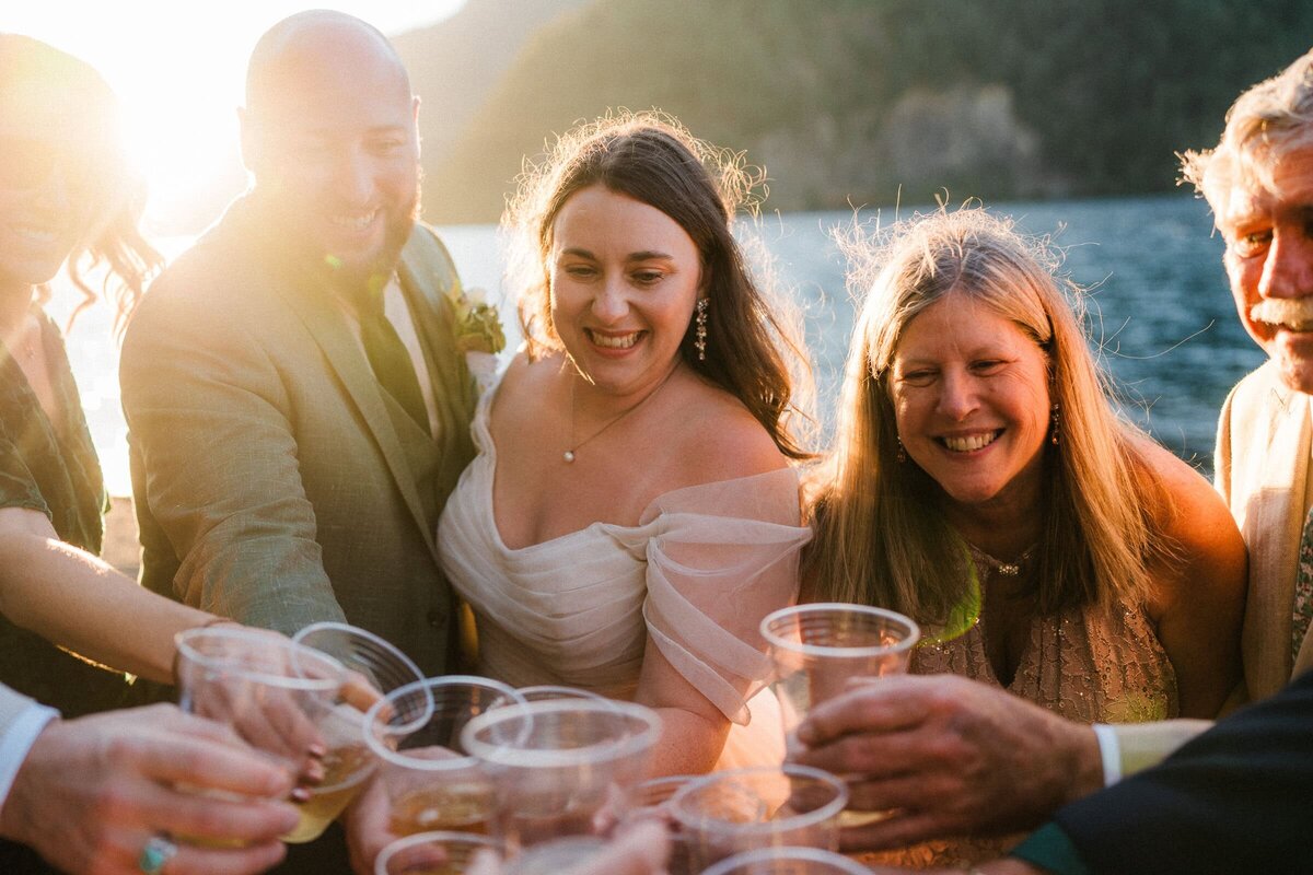 an Washington elopement toast surrounded by family with golden light pouring over shoulders.