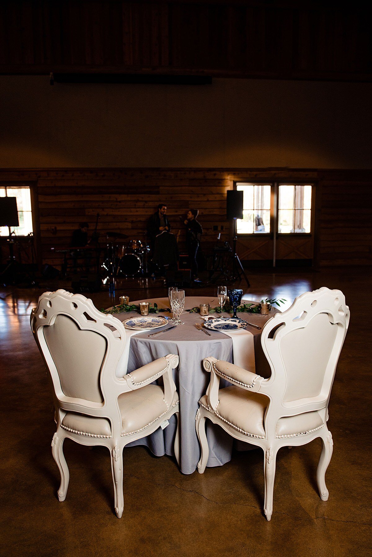 two large intricately carved  ivory throne chairs at a sweetheart table with a dove gray table cloth.