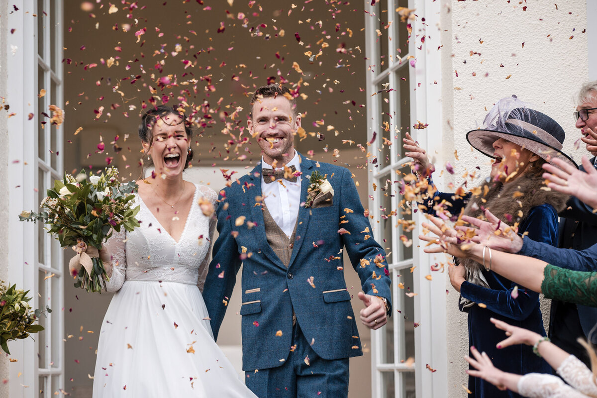 Bride and Groom showered with confetti as they leave their wedding ceremony at Rockbeare Manor