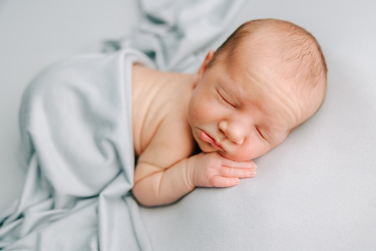 newborn portrait of boy who is sleeping on blue blanket