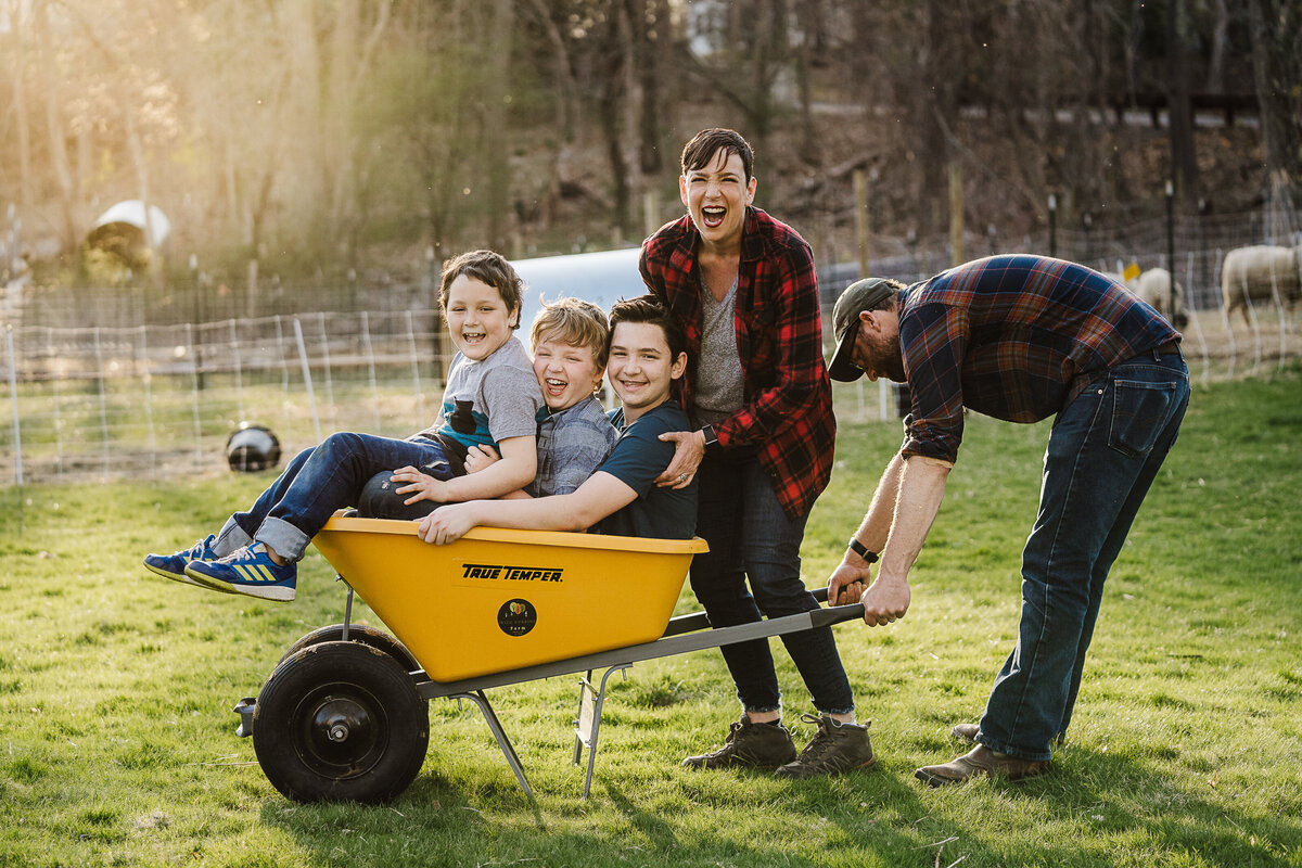 family pushes children in wheelbarrow