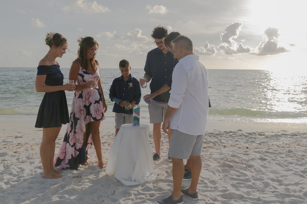 Family filling sand bottle at beach wedding