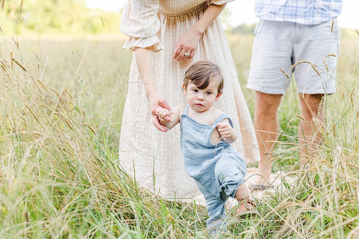 boy walks holding mom's hand during Family photo session with Sara Sniderman Photography at Heard Farm in Wayland Massachusetts