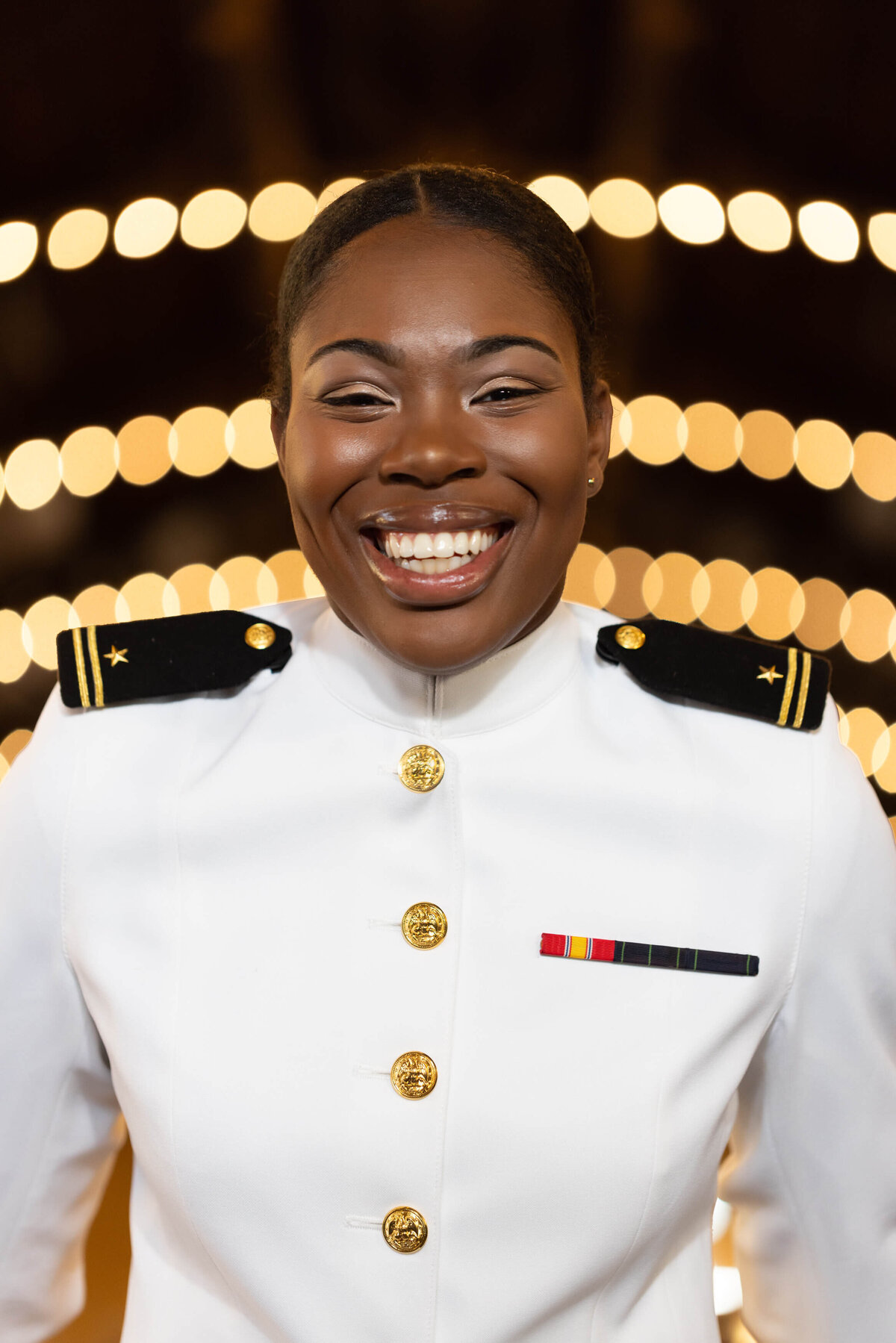 Midshipman Smiling in Senior photos with lights at the Naval Academy.