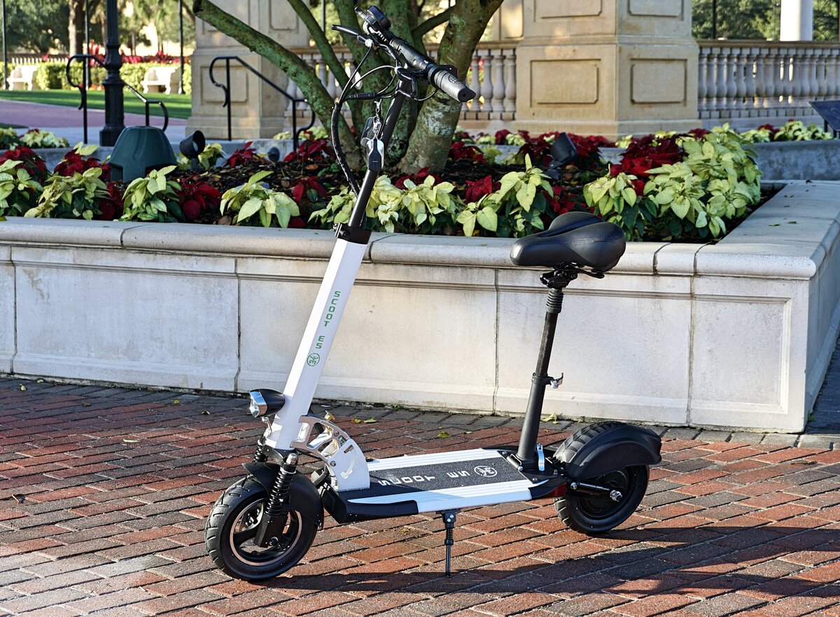 Lady walks upstairs holding Red Scoot E-3; V&D Electric Bikes