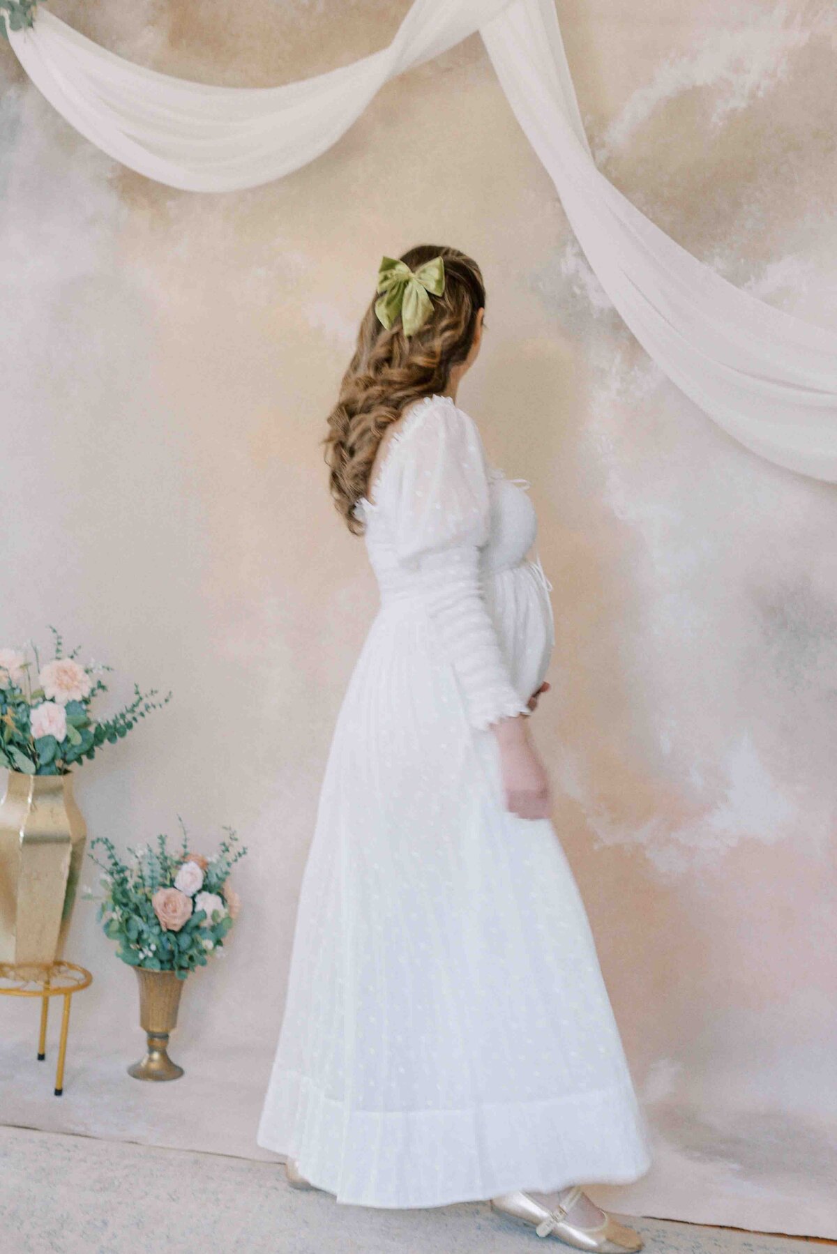 Richmond maternity photography | Light and airy photo of a pregnant mother in a white dress walking across a watercolor pink wall by Jacqueline Aimee Portraits