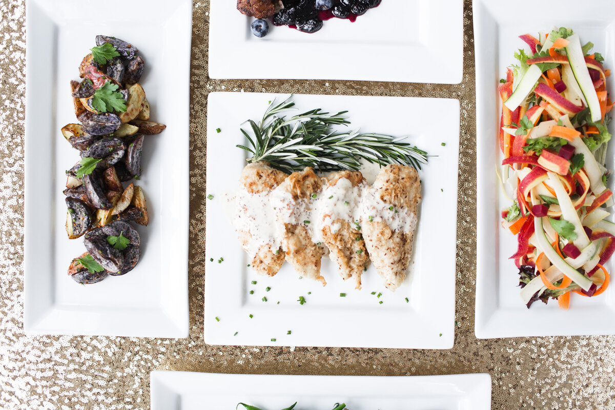 image of fingerling potatoes, chicken milanese and a shaved vegetable salad being served family style at Willowbrook wedding venue