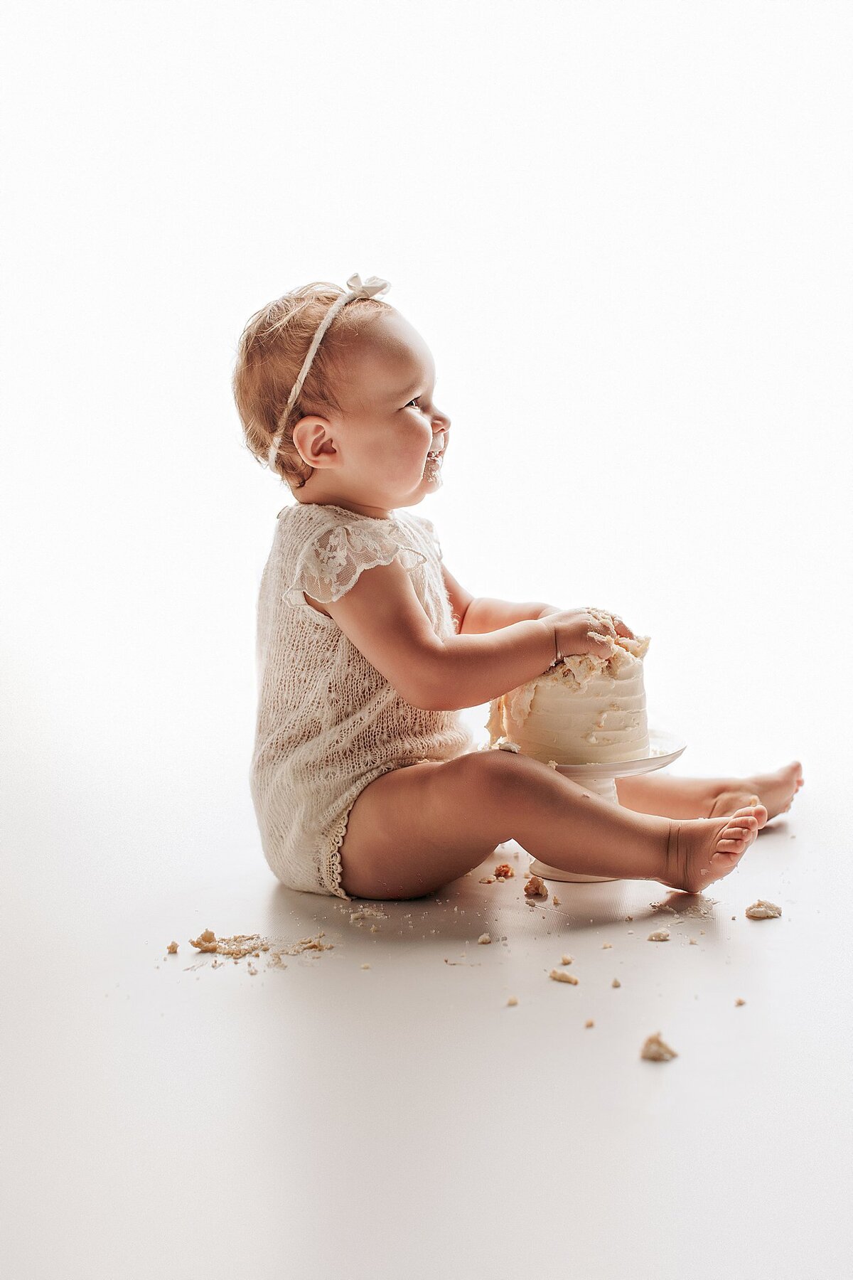 Baby covered in frosting during playful cake smash milestone session
