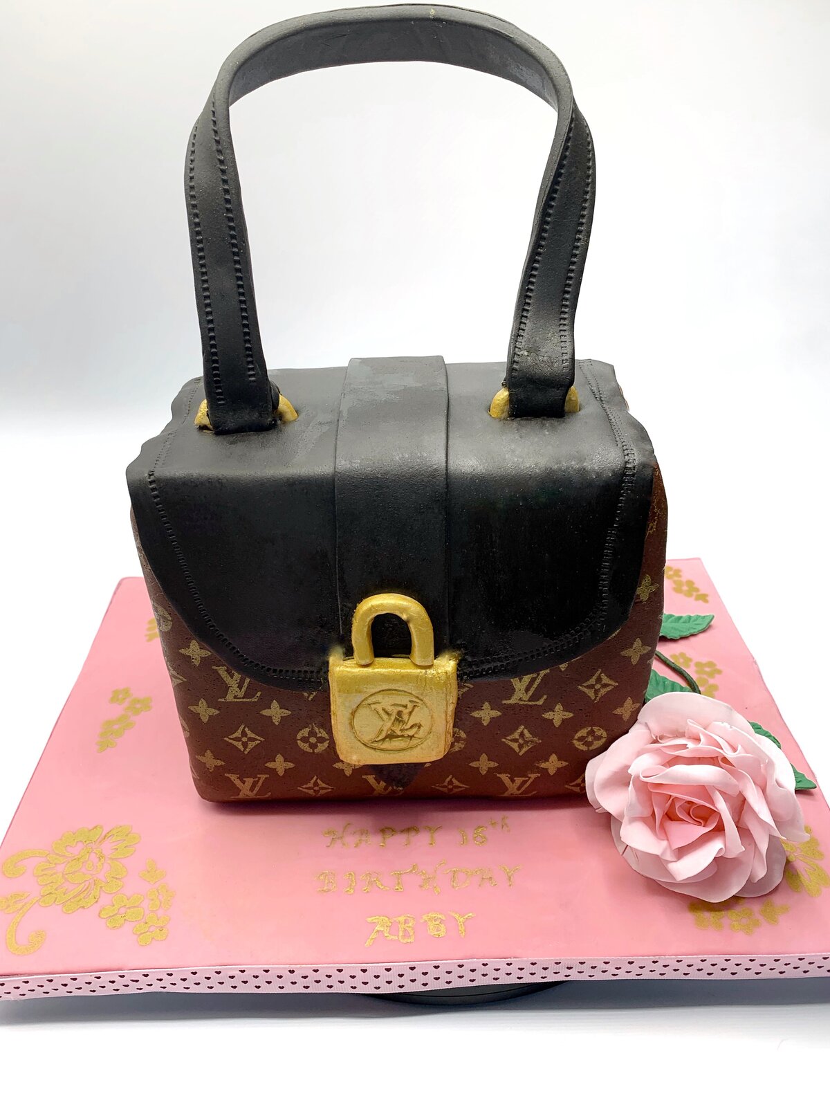 Black and brown Louis Vuitton inspired handbag cake with gold lock and LV logo accents.
