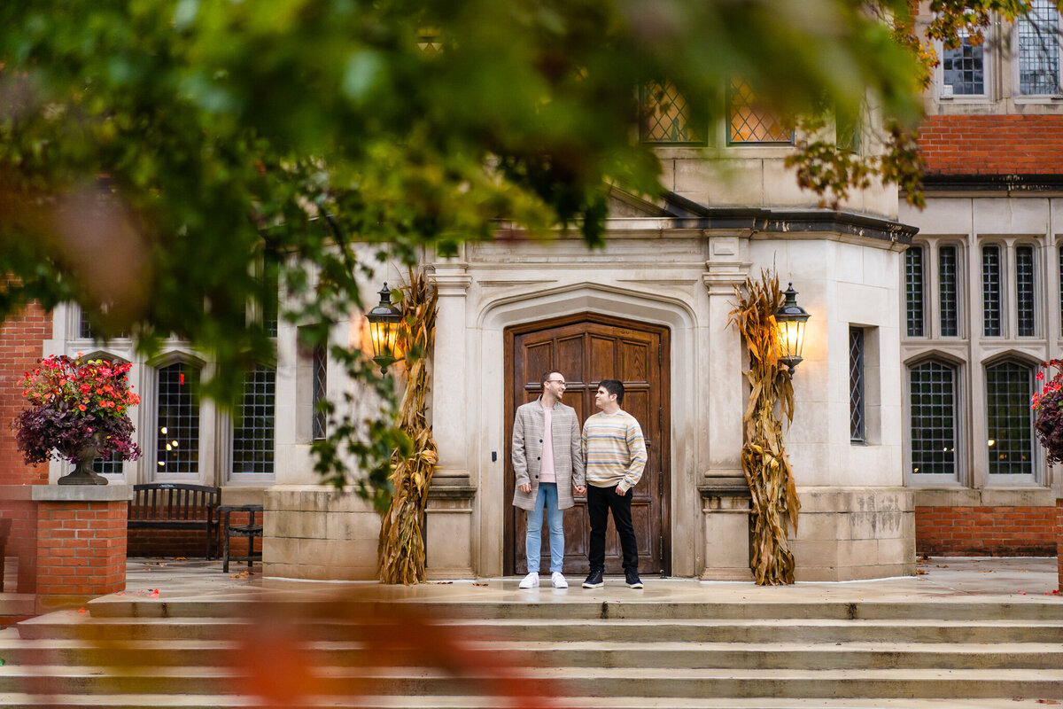Engaged LGBTQ+ couple, Doug and Shawn, hold hands and look at each other in front of Jeffrey Mansion in Columbus Ohio.