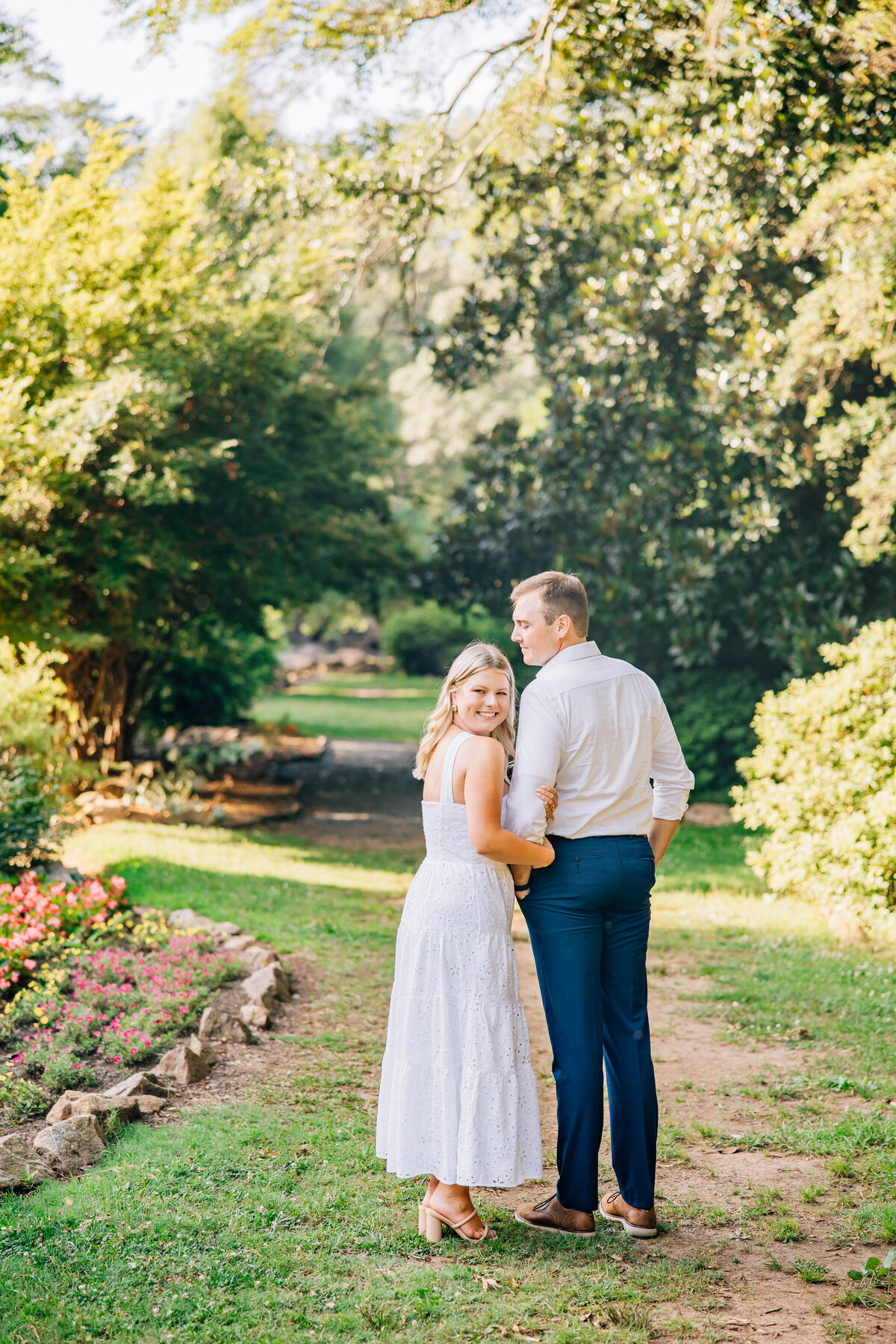 couple holding hands with girl looking back at the camera and white dress on