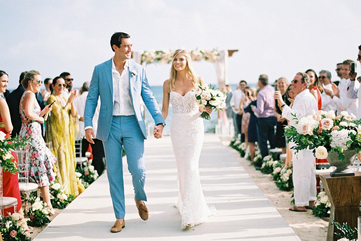 Couple walking down the aisle during their ceremony at their destination beach wedding