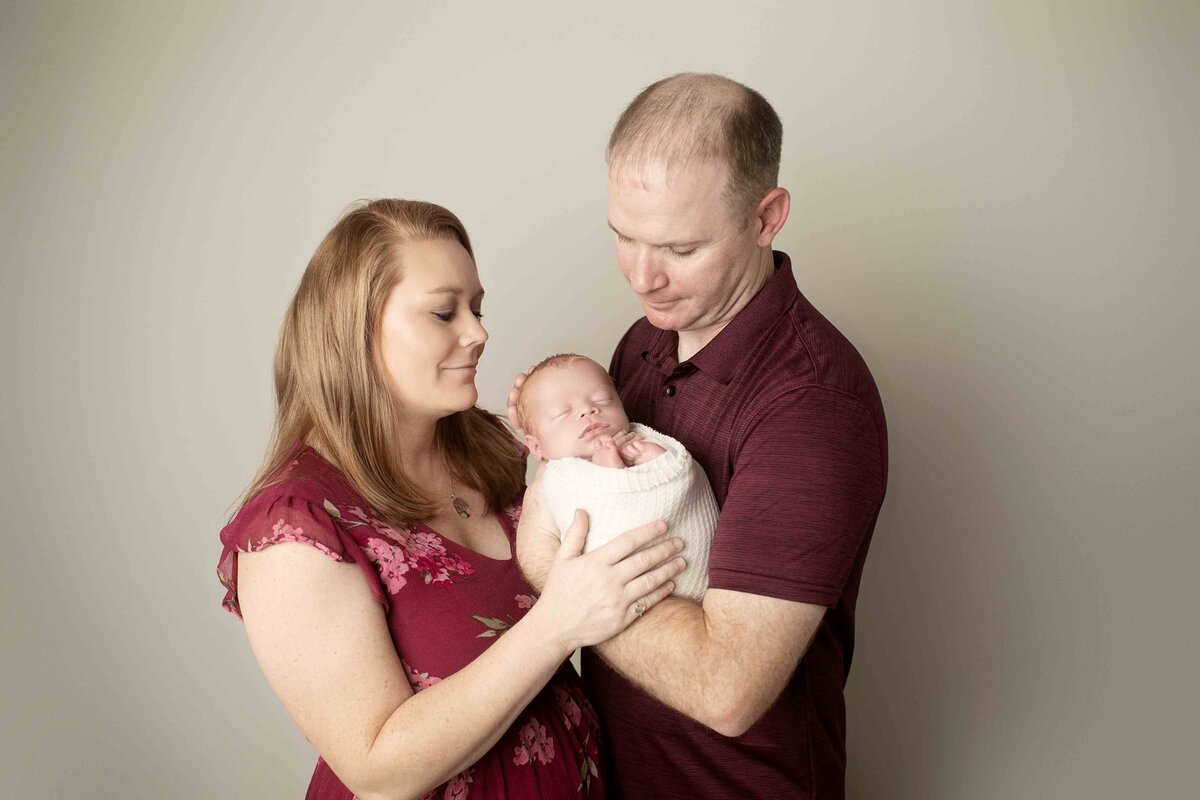 Parents lovingly pose with their newborn son, sharing a quiet, joyful moment