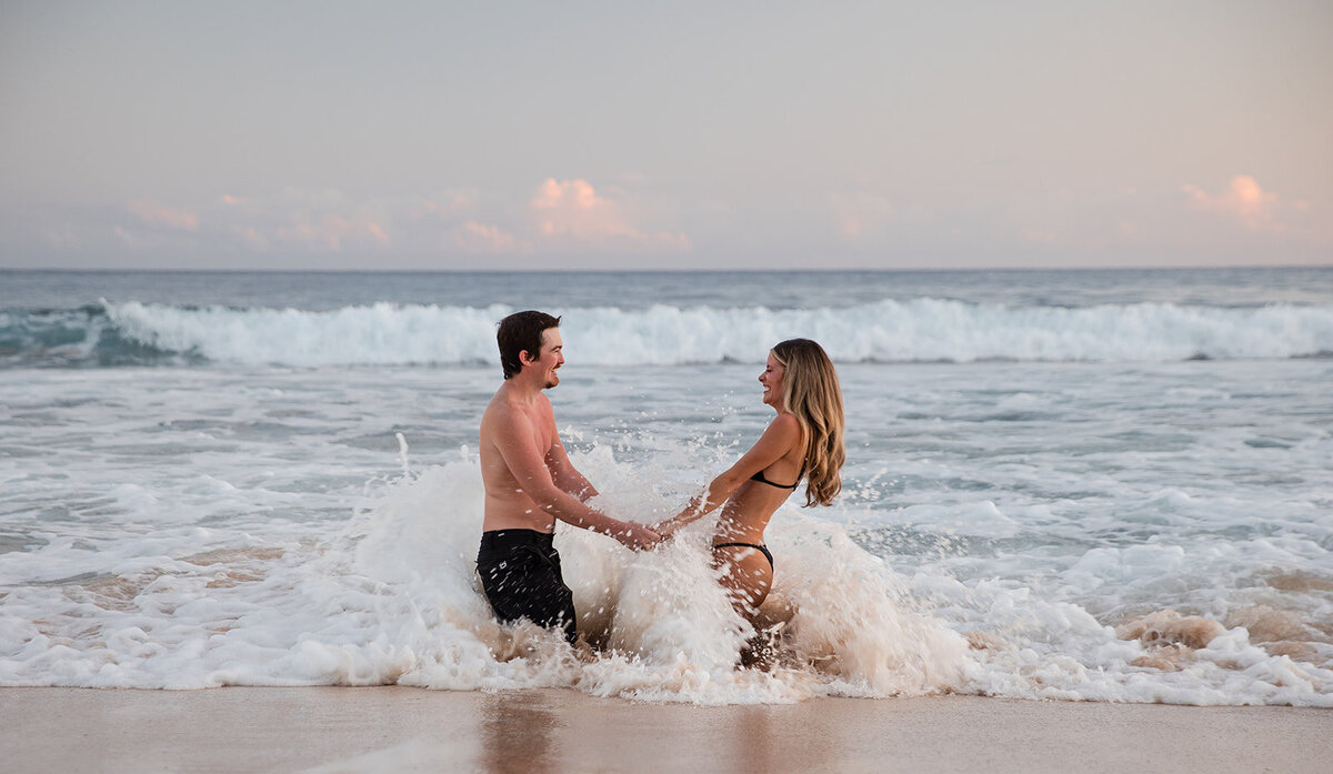 wife and husband getting splashed by ocean water