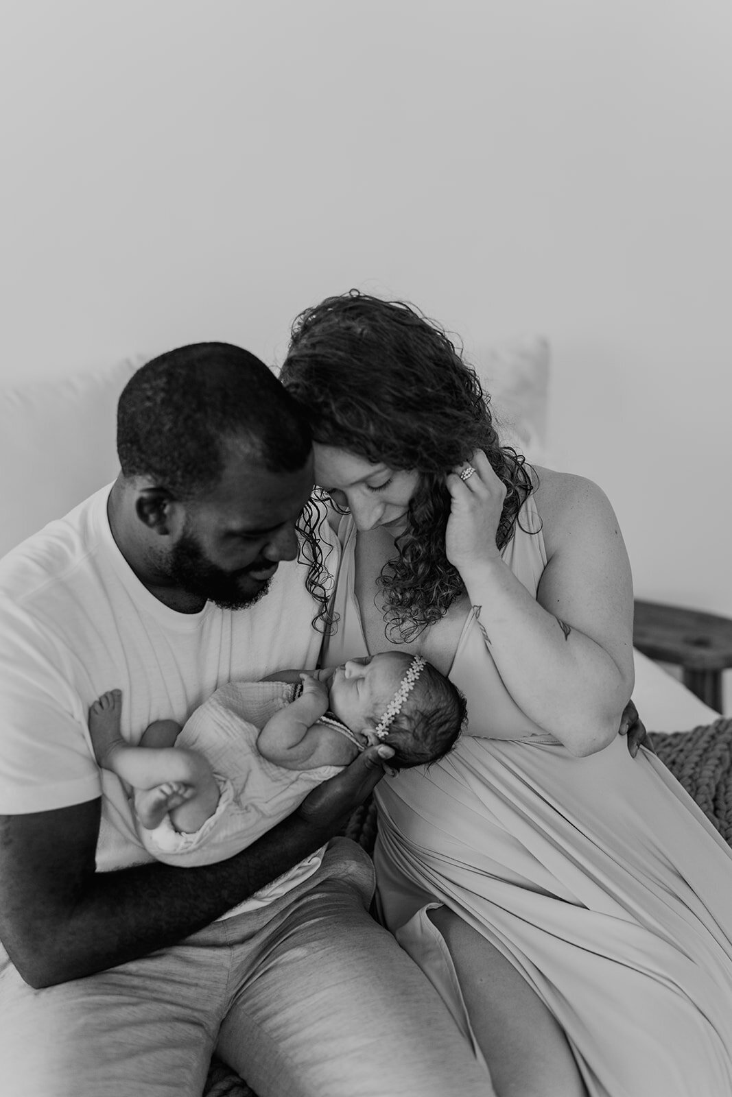 black and white of an interracial couple holding their newborn
