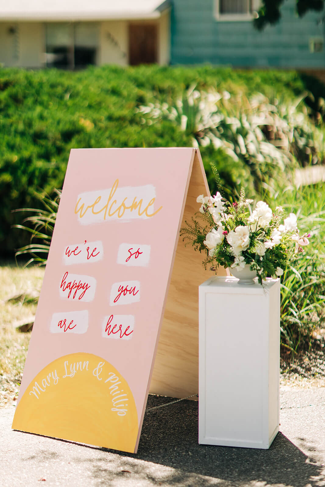 A bouquet of flowers on a pedestal next to a wedding welcome sign.