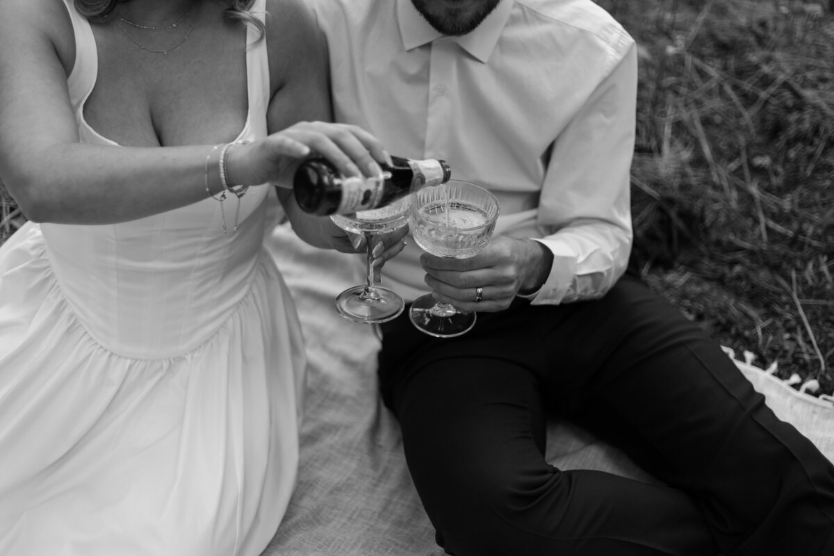 Bride pouring Martinelli's apple cider into her and her groom's glass, in black and white.
