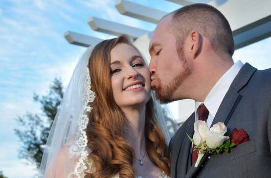 Red haired bride with classic bridal makeup being kissed by groom