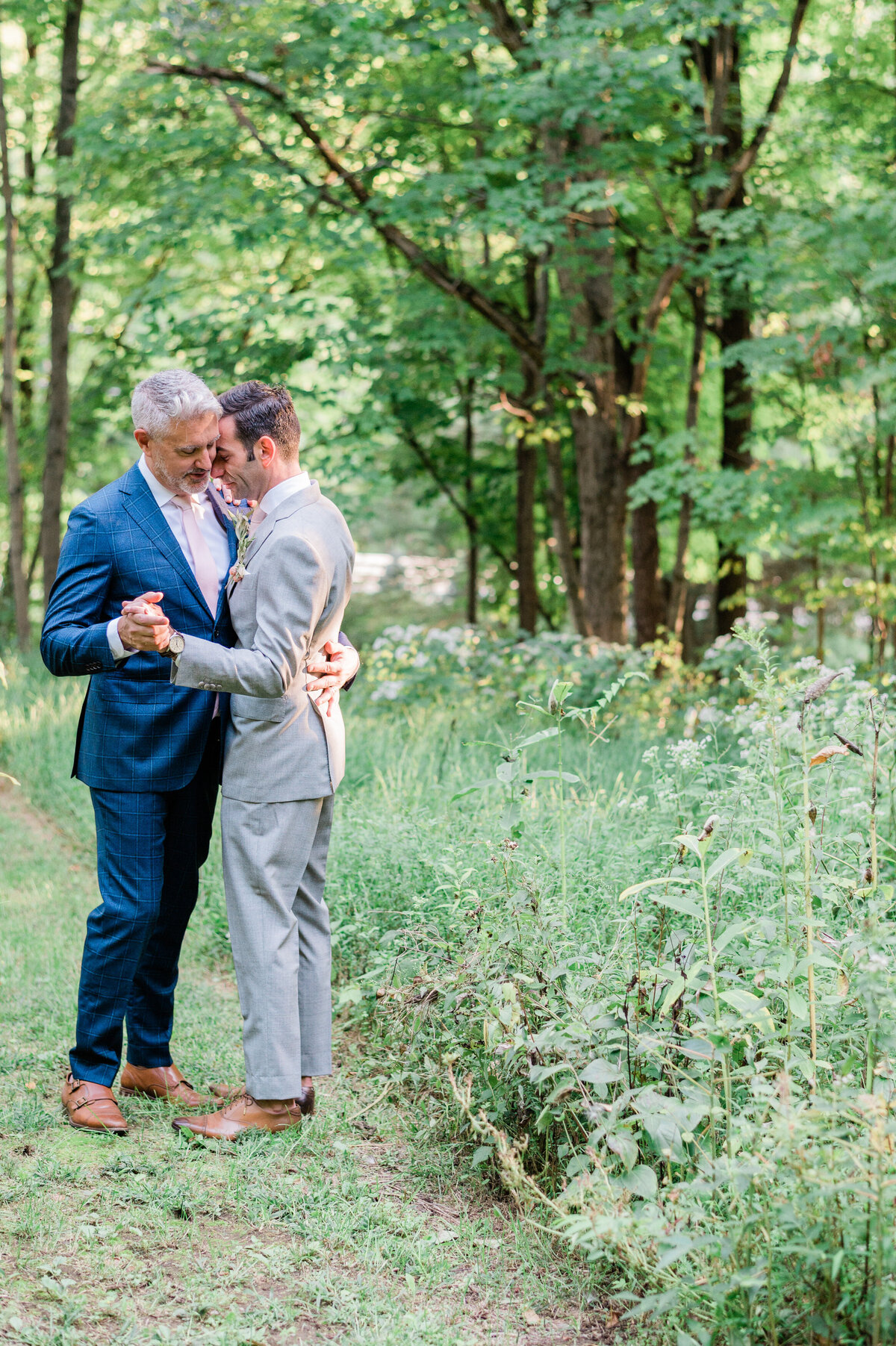 Grooms dance in the grassy yard together 