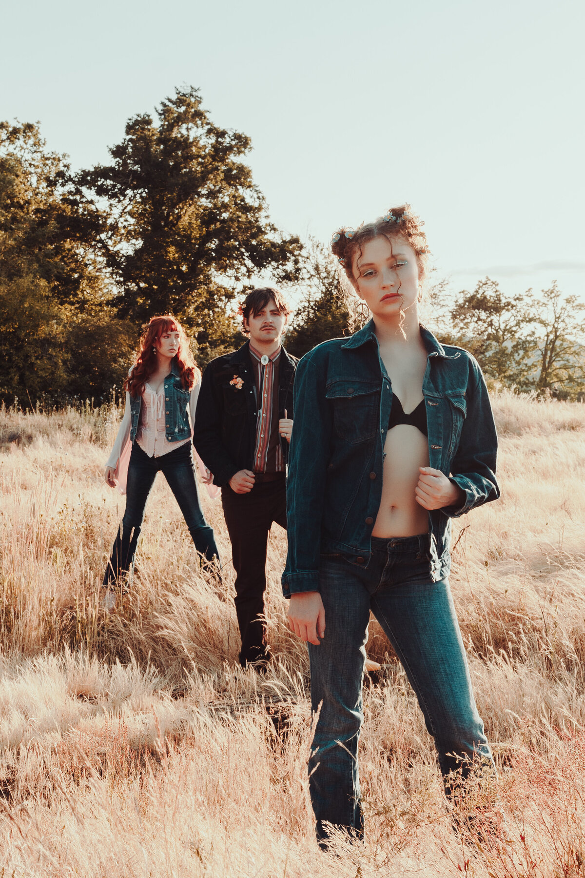 Indie music group walking through dry grass field in bold styling – artistic brand photography for musicians by Mewphotovideo