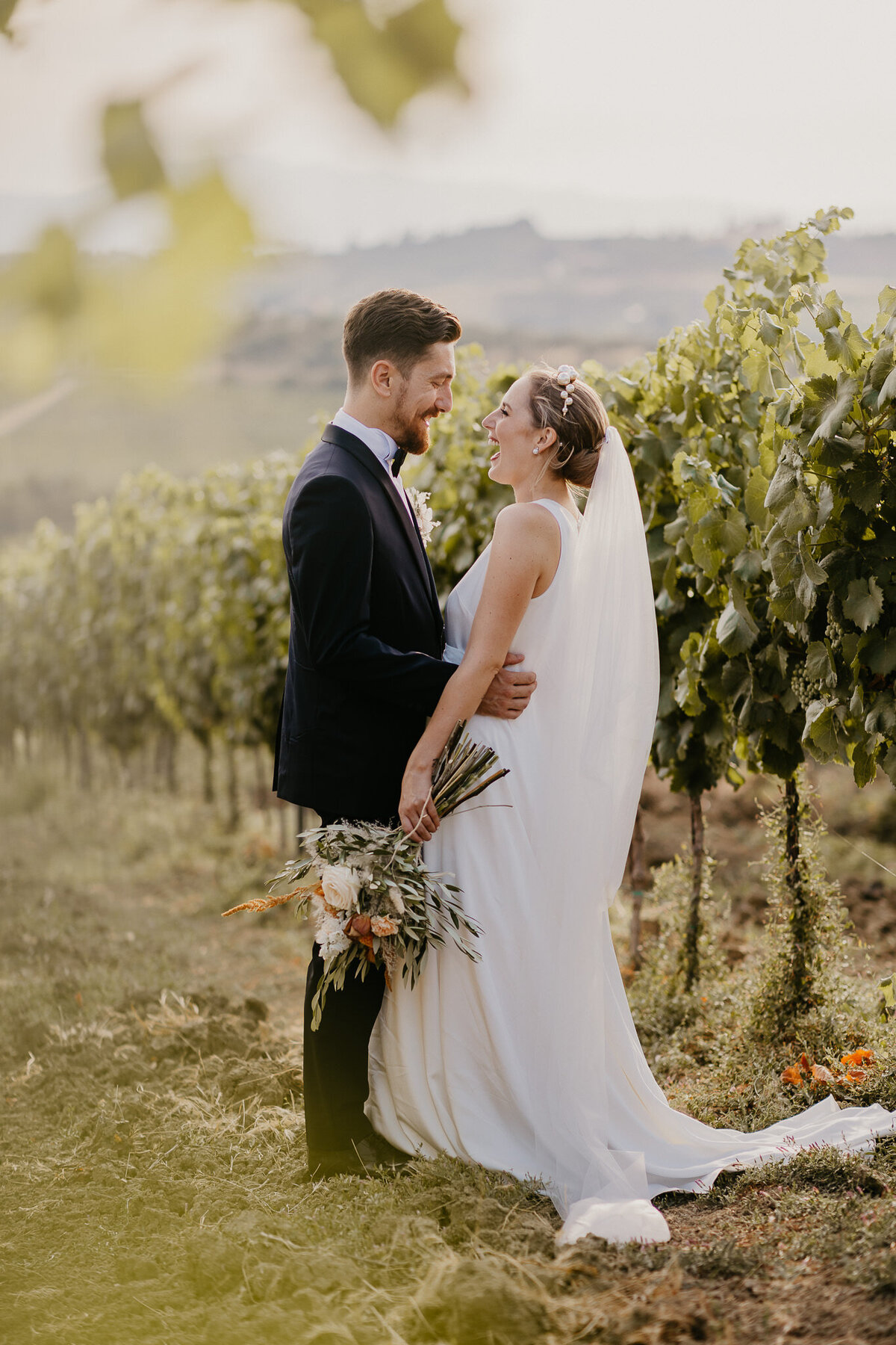 Bride and groom embracing among vineyard rows near Villa Dianella, authentic Tuscany wedding photographer.