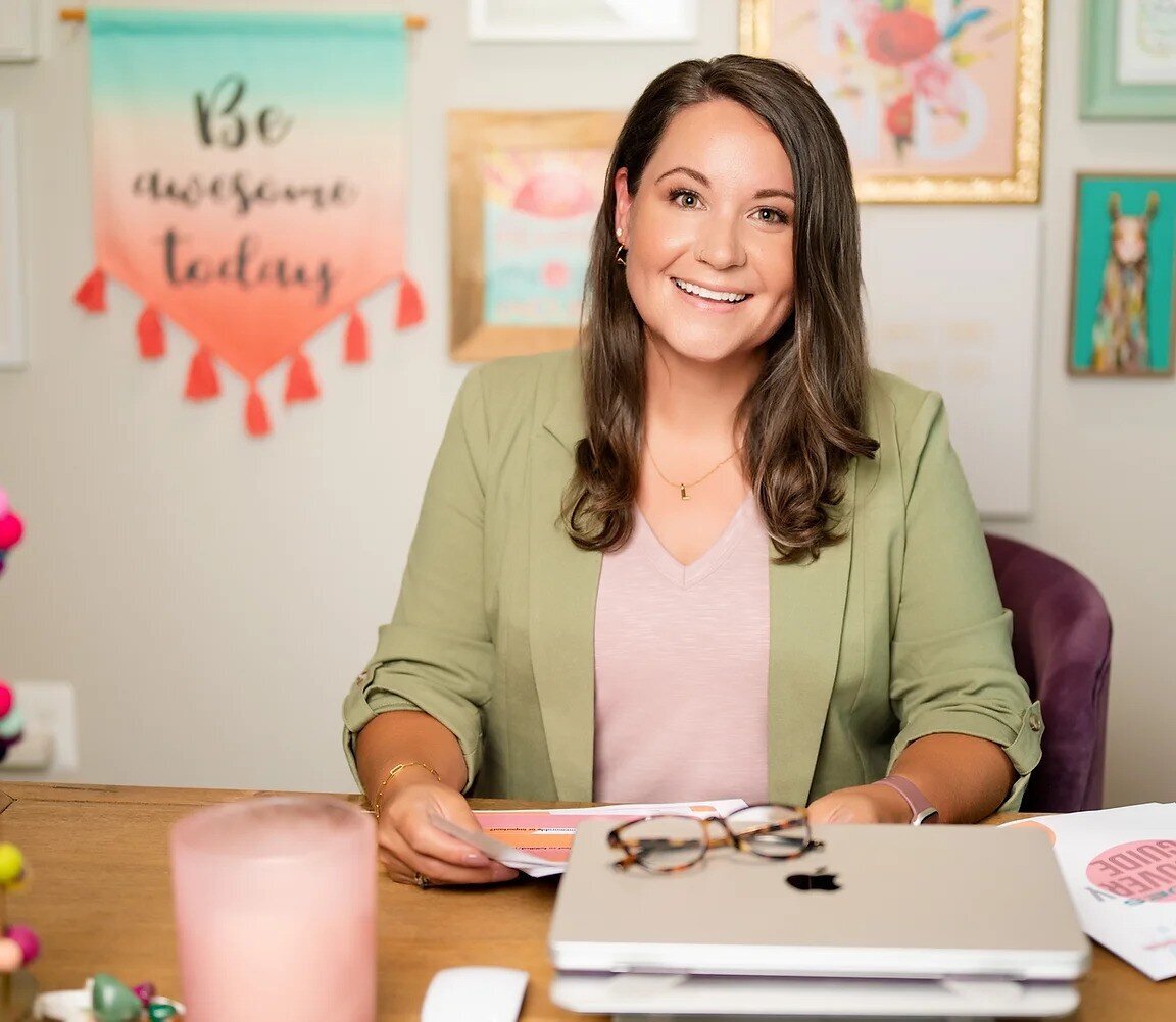 Therapist with brunette hair sits at a desk wearing a sage green blazer