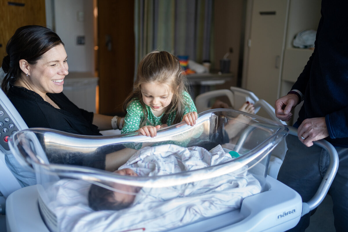 Big sister peeking over bassinet