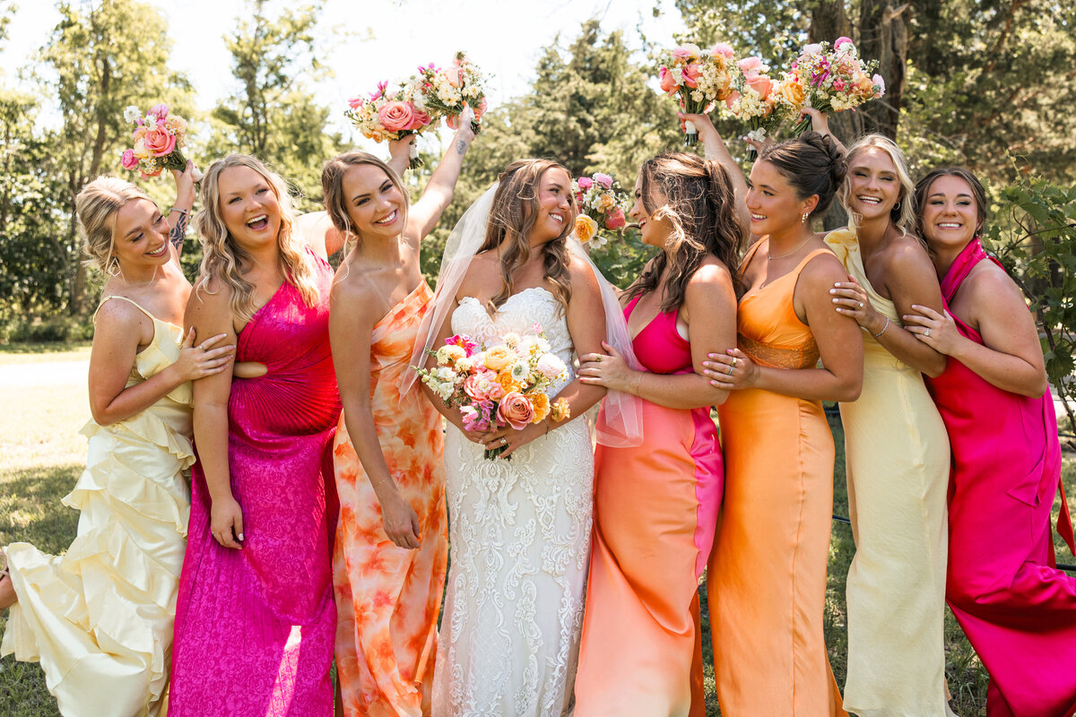 Bride laughing with bridesmaids in a fun candid moment during wedding photos at Hidden Vineyards in Maize, Kansas