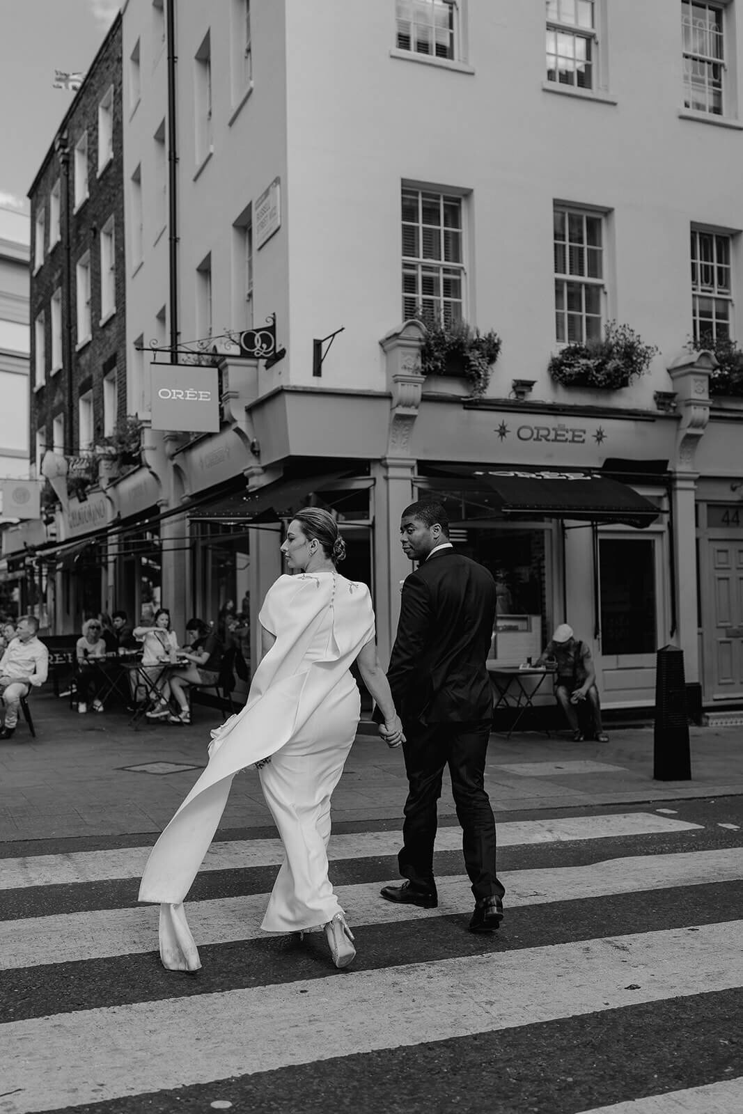 bride and groom hold hands to cross a zebra crossing on the streets of London as they head to their intimate wedding party at the nomad hotel
